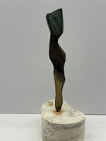 Front view of sculpture on marble base against neutral backdrop