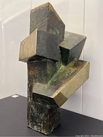 Front view of sculpture showing intersecting geometric forms and patina