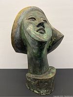 Angled front view of bronze head sculpture showing overall form and patina