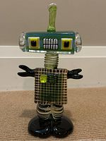 Front view of the glass robot sculpture showing head, torso and feet