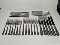 Overview of entire set with forks and knives laid out on surface