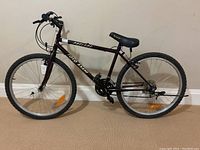 Side view of the entire bike showing the maroon frame, tires, handlebars, and seat.