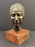 Front view of bronze sculpture of woman's head on wooden base