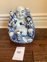 Front view of the blue and white Buddha statue with five children showing detailed facial expressions and painted clothing.