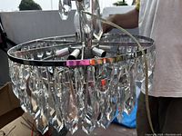 Top view of round silver metal frame chandelier with hanging clear crystal prisms and missing crystals.