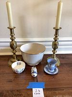 Overview photo of lot showing all items together: two brass candlesticks with candles, large white bowl, small floral bowl, blue and white porcelain shoe, blue cup and saucer.