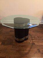 Full front view of the dining table showing the clear glass dodecagon top and black base