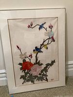 Full view of framed fabric art showing birds on branches with flowers.