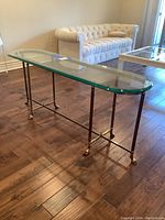 Side-angle view of glass console table showing brass frame details and glass top.