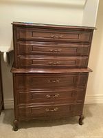 Front view of the large wooden dresser showing six drawers and brass handles, with a glass top.