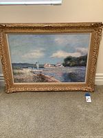 Full front view of the framed lake painting displayed against a wall on carpeted floor.