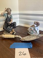 Photo showing two figurines and the serving utensil on wooden floor.