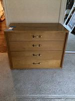 Front view of the wooden chest dresser with four drawers and metal handles.