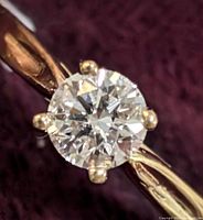 Close-up image of the 10K gold ring centered on the lab diamond, showing the four-prong setting and polished band against a dark fabric background.