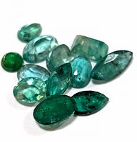 Loose emerald gemstones arranged on white background