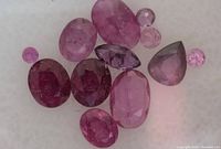 Loose ruby gemstones in various cuts and colors on white background.