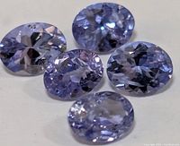 Close-up of five oval faceted tanzanite gemstones showing their blue-violet color and clarity.
