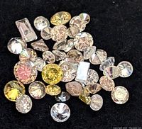 Loose diamonds arranged on black felt background showing variety of cuts and colors