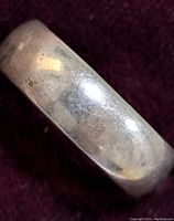 Close-up front view of the plain silver ring showing its smooth rounded band and polished surface with light wear marks.