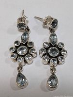 Pair of sterling silver drop earrings with faceted blue topaz stones, shown front view.