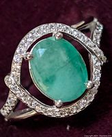 Close-up of the front view showing oval emerald surrounded by CZ halo on silver band