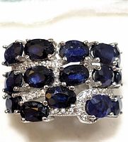 Close-up front view of a sterling silver ring with multiple oval sapphires and clear accent stones