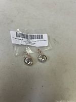 Pair of 18K rose gold-plated earrings with large clear Swarovski crystals and packaging label.