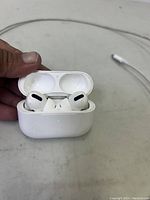 Open charging case displaying AirPods Pro earbuds inside with visible scratch marks on case