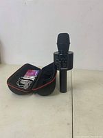 Full view of Bonrok wireless Bluetooth karaoke microphone standing upright next to semi-rigid zippered carrying case containing cables.