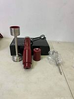 Photo showing Curtis Stone red handheld electric mixer, blending shaft, whisk attachment, and box.