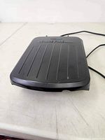 Side view of compact George Foreman electric grill showing ridged grilling surface