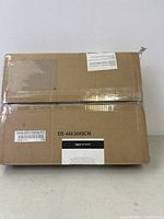 Sealed cardboard box with Amazon Commercial label. Box size indicated as 44x34x8 cm. Label reads 'Heavy Duty Waterproof Clear Mesh Tarp' in multiple languages.