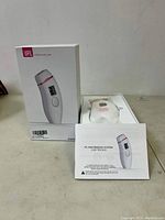 IPL hair removal device in packaging with user manual displayed in front.