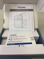 Open box with installation instructions and warranty card inside of Teeho TE001 keypad deadbolt set.