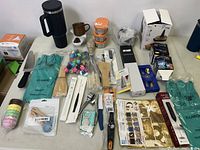 Multiple new kitchen items including gloves, utensils, containers, and kitchen gadgets arranged on a table.