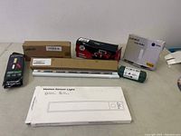 Overview photo of lighting lot items on table including motion sensor light, LED bulb, flashlight, and boxes.