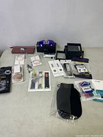 Full lot in a single image: multiple packaged watch bands, sunglasses with purple lenses in a black case, small costume jewelry packages, and other accessories including protection and mounting frames.