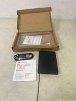 Seagate Portable External Hard Drive, USB 3.0 cable, user manual, and packaging laid out on a surface.