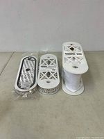 Three trims displayed side-by-side: rhinestone strip, pearl trim strand, and white chiffon ruffle on a spool.