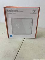 Front view of the Alarm.com smart thermostat box showing model image and branding.