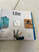 Front of the Tile Mate box showing the Tile device and its usage examples with keys and wallet.