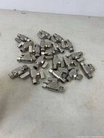 Overview of about twenty stainless steel ball valves with lever handles scattered on a surface.