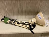 Photo of the lamp laid on shelf showing full length with coiled cord and clamp base