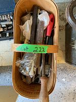 Top view of wooden basket containing assorted small hand tools including clamp, files, screwdriver, and hex key set.