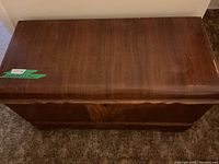 Front view of wooden cedar chest showing smooth top surface with some wear and the lock area without a key.