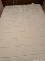 White heated mattress pad spread out on bed surface showing overall condition and quilt stitching.
