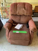 Front view of rust-colored fabric electric recliner chair with remote and manual on seat
