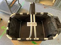 Top view of black fabric folding shopping basket with silver frame and foldable handles, showing LOT 199 label inside.