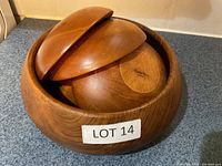 Wood salad set with large bowl containing smaller bowl and two utensils.