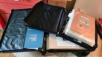 Overview photo showing two binders, one black and one white, used to store small matted artworks in plastic sleeves.